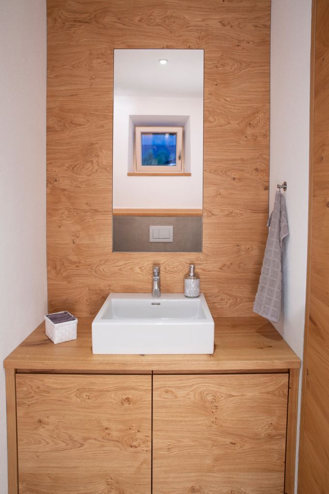 Ein Stauraum im WC mit Waschtisch in Eiche und Aufsatzwaschbecken