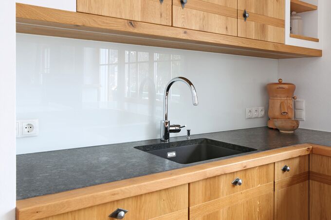 Arbeitsplatte der Küche in Naturstein mit Massivholzumrahmung, integrierter Spüle, Glasrückwand