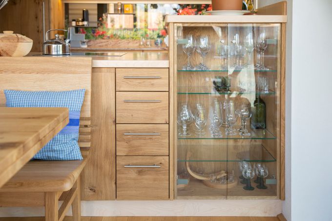 Die Rückseite der Küche bietet eine Sitzgelegenheit sowie Schubladen und eine Glasvitrine mit viel Stauraum