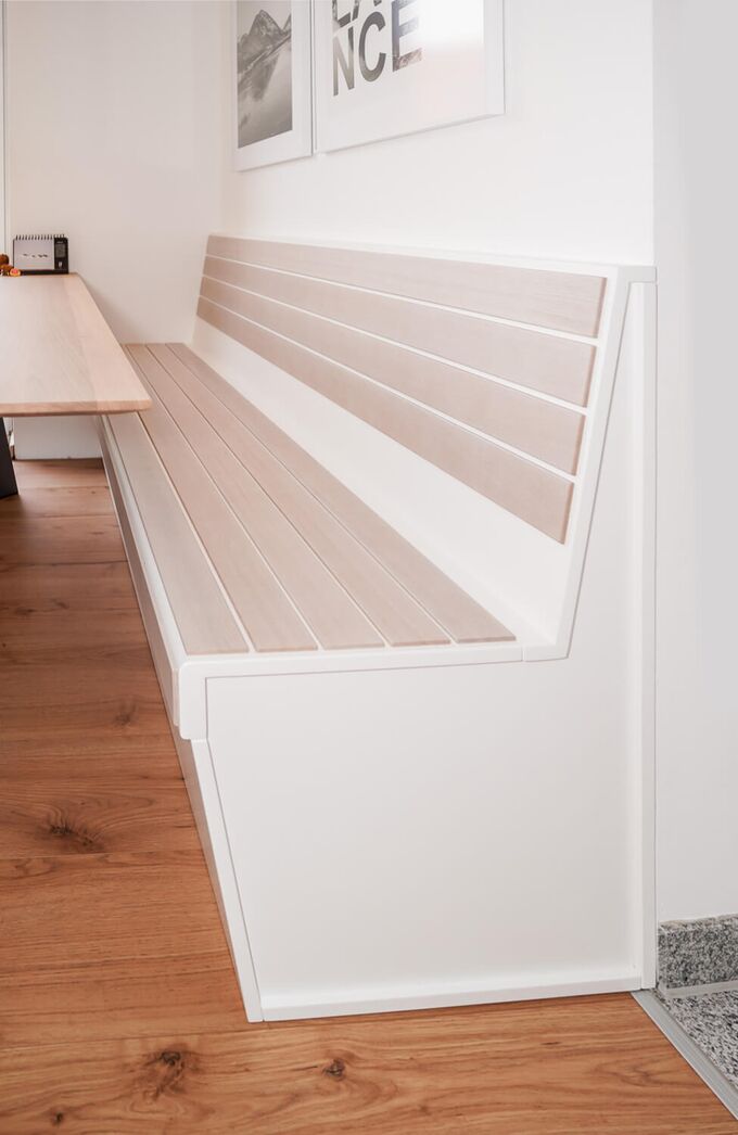 Weiß lasierte Eichenplanken zieren die weiße Sitzbank. Die Sitzfläche kann nach oben geklappt werden, darunter befindet sich ein Stauraum.