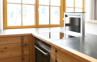 Die Kochstelle in dieser Küche wurde mit einem Dunstabzug ausgeführt, der hochfährt und auch als Spritzschutz dient