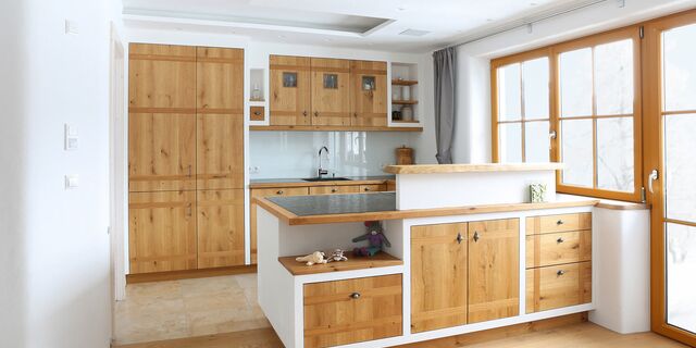 Traditionelle Küche mit Massivholzfronten und Mauereinfassung, Arbeitsplatte Naturstein mit Massivholzumrahmung