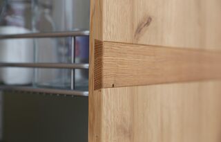 Detailbild von einem Auszug in massiver Eichenfront mit sichtiger und zierender Gratleiste