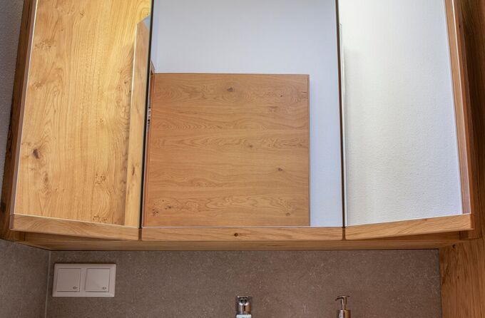 Ein Waschtisch in Eiche mit weißem Corian Becken und Spiegelschrank